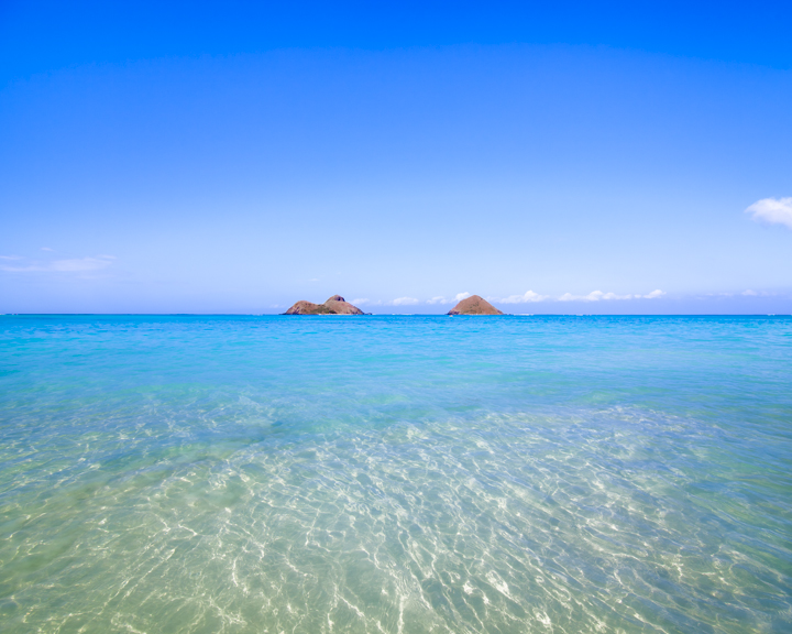 Ocean waters, small islets and blue skies over Lanikai Beach on Oahu.